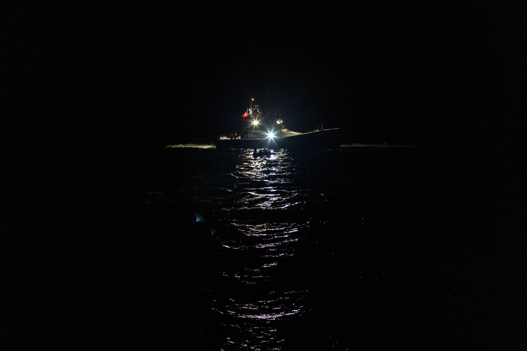 Europe, Turkey, Dikili. 9 Afghan citizens can be seen on a small engineless raft in the northern Aegean Sea at 4:30am, with the Turkish coastguard in the rear of the shot. They all claim to have landed on the nearby Greek island of Lesvos for around 12 ho