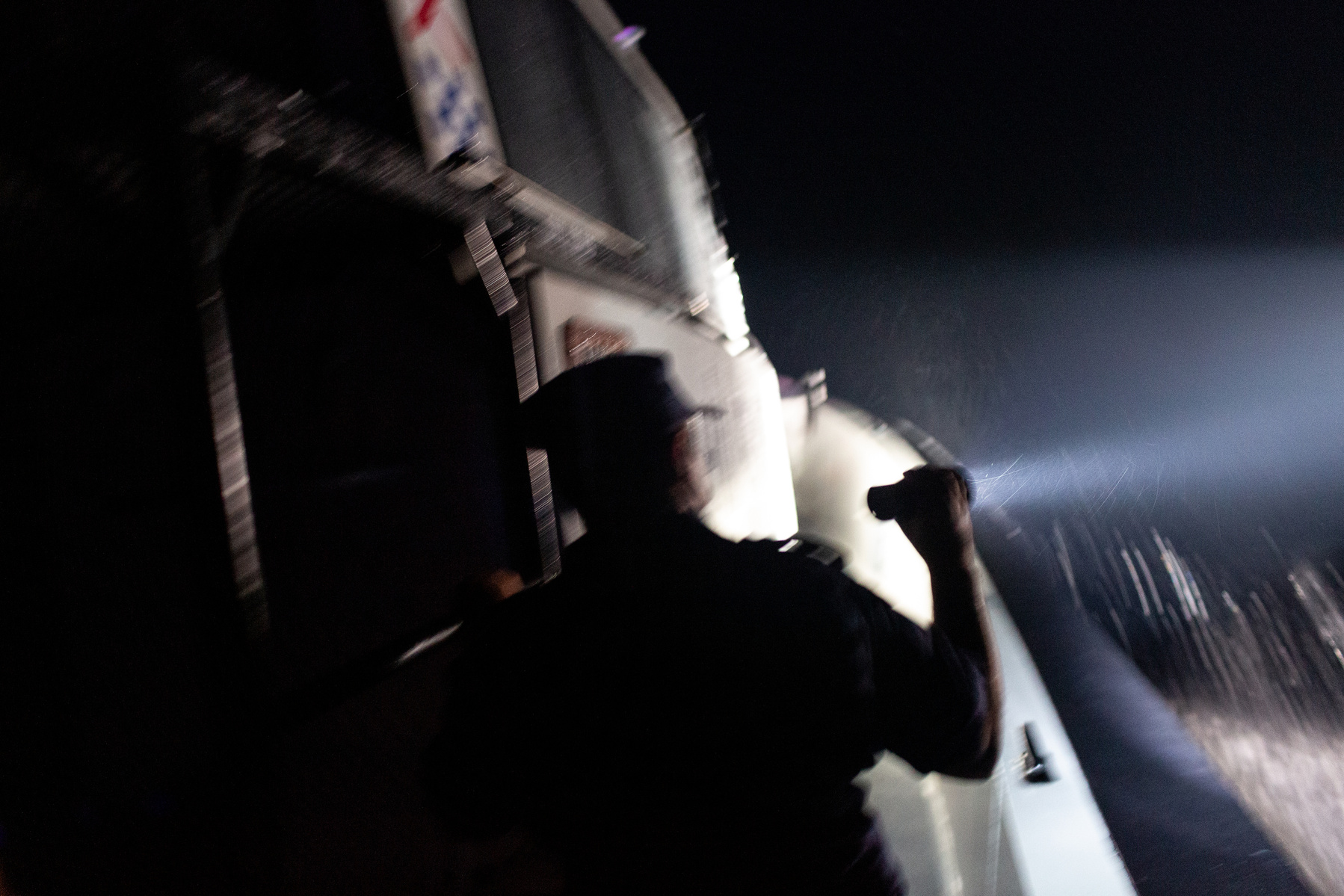 Turkish a coastguard shines a light on a nearby Greek coastguard patrol boat, and into the black night of the Aegean waters, in search of two reported rafts of migrants drifting on the border of Turkish and Greek territorial waters.