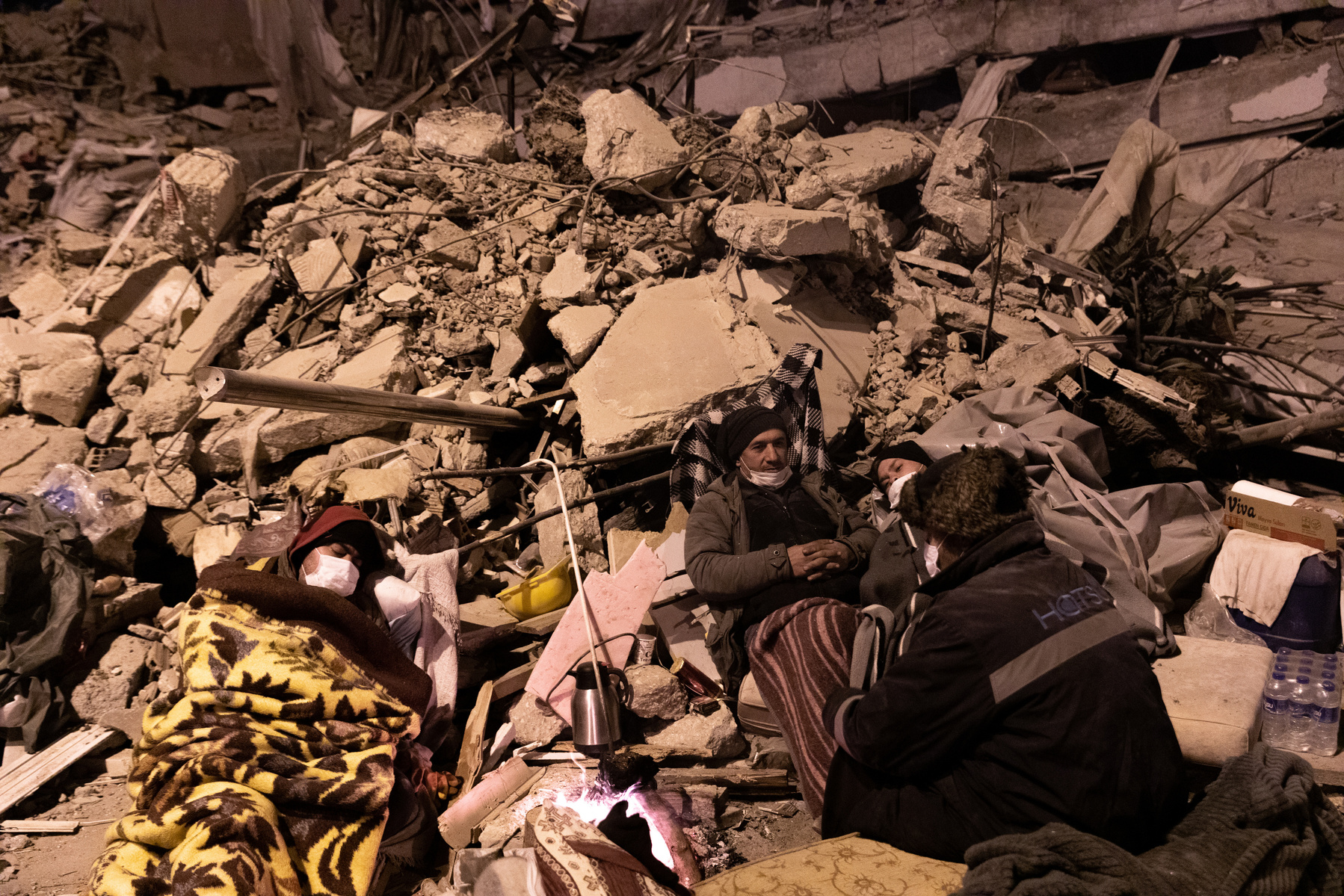 Sleeping in the rubble ruins of his home - former residents of apartment blocks destroyed by the earthquake, wait next to rescue workers, for news on their loved ones.
