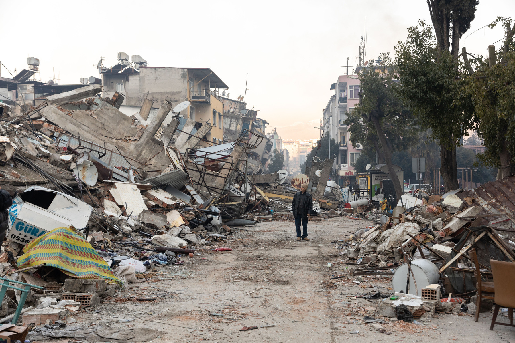 An earthquake survivor walks down the destroyed ruins of a central street in Antakya, on the corner of Kurtulus Cad. in Hatay, Turkey