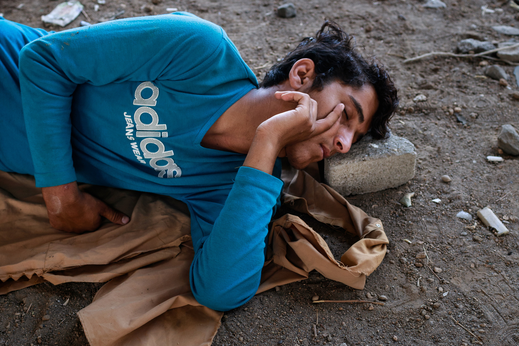 A young man from Afghanistan sleeps using a brick as a pillow, under a bridge, next to some railway lines on the outskirts of the eastern Turkish city of Tatvan. As Afghanistan comes under Taliban rule, tens of thousands have fled westward through Iran, a