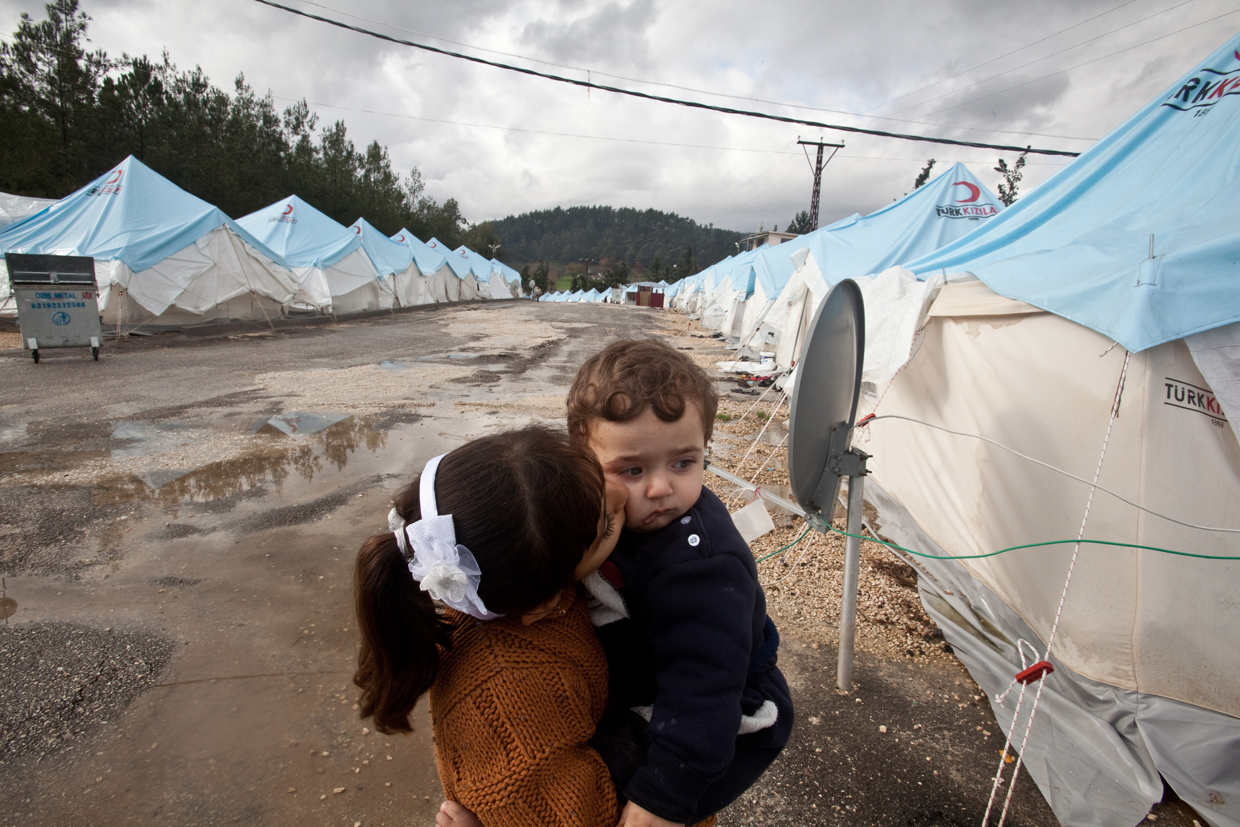Bara'a kissed her younger cousin under rainy skies at Yayladagi refugee camp for Syrians in southern Turkey. 12/21/2012 Bradley Secker for the Washington Post