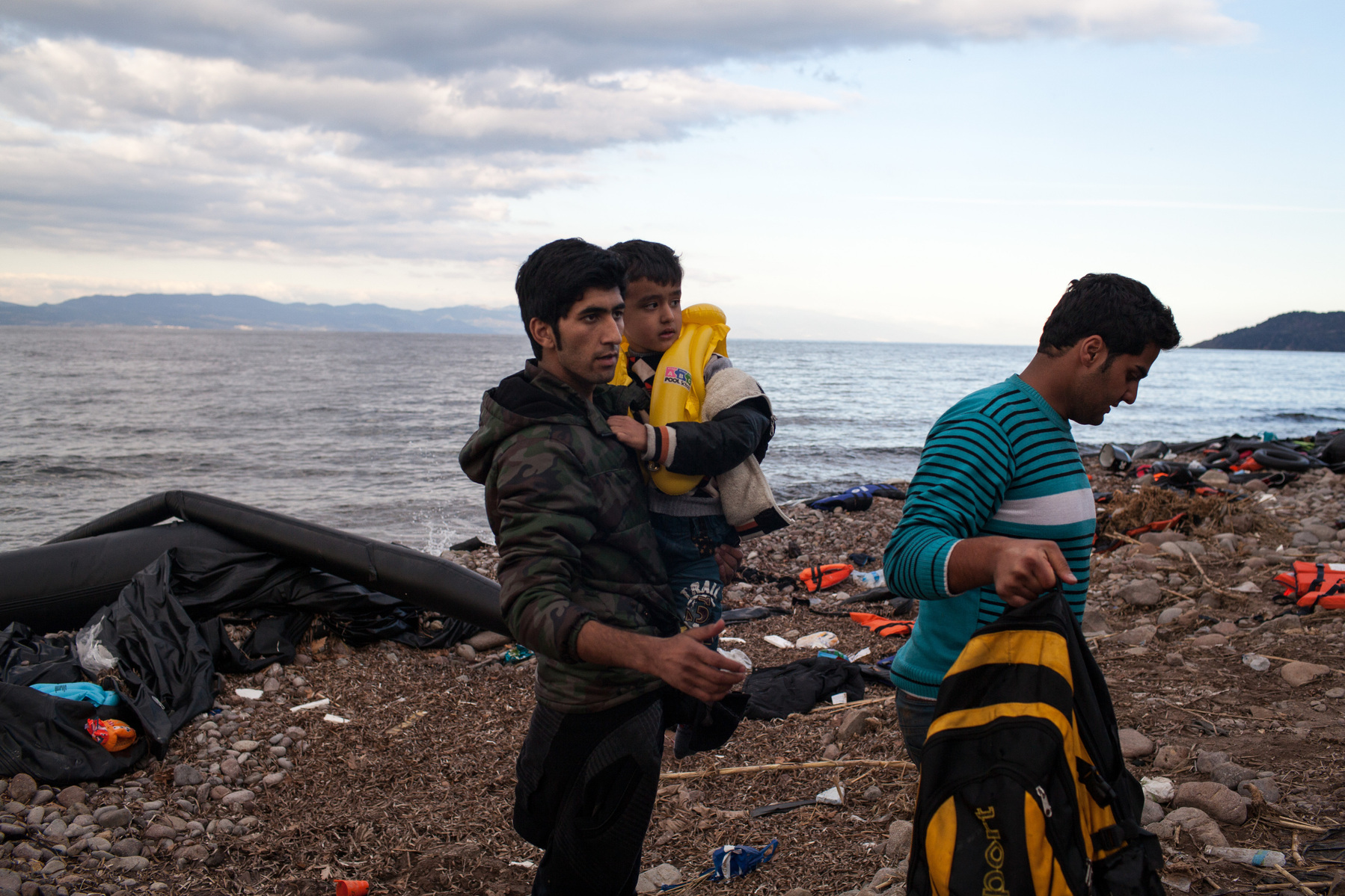 Newly arrived migrants and refugees to Greece, stand on a beach on the northern coastline of Lesvos island.
