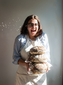 baker with stack of sourdough bread