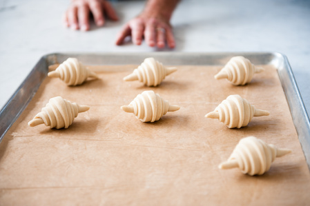 unbaked croissants with baker hands