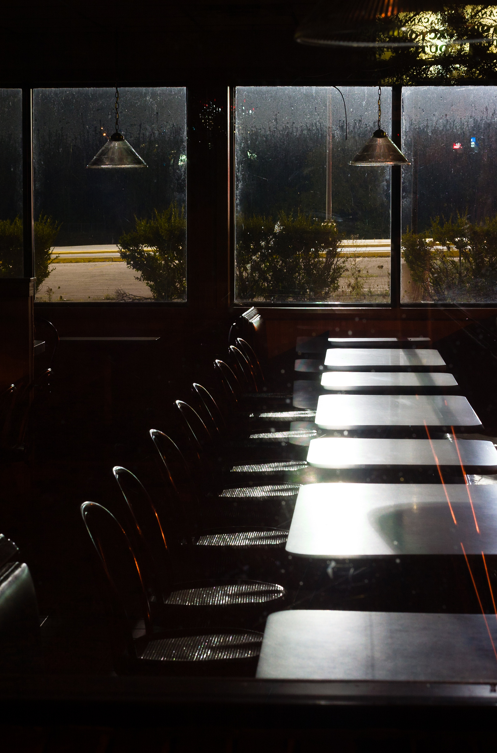 The tables of an abandoned Burger King restaurant at night.