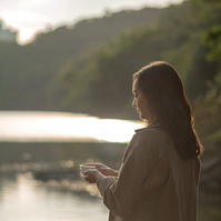 Woman holding a cup of tea by a lake in HK