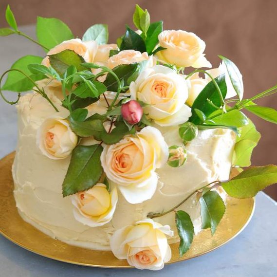 Orange Cake covered with Beautiful Fragrant Garden Flowers, Custom Made Organic Cake with Light yellow flowers. 
