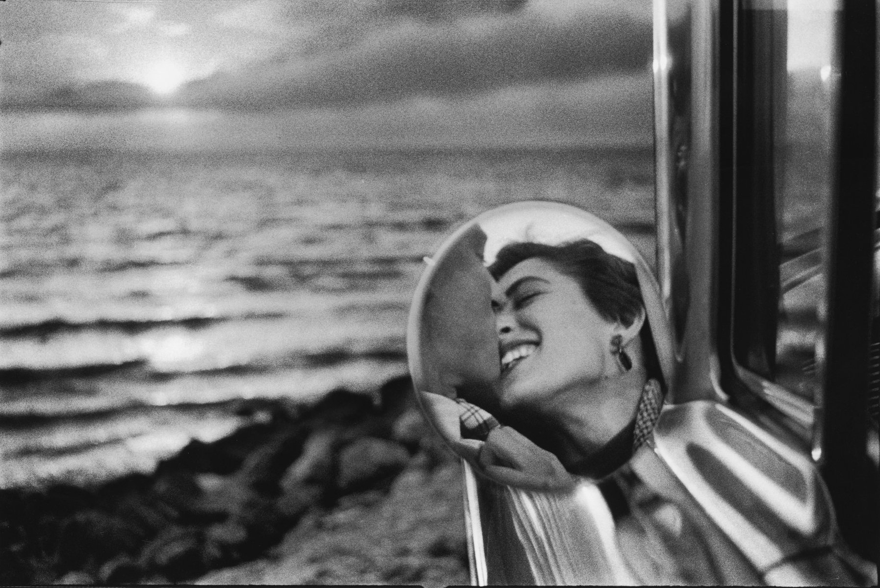 Découvrez une photographie iconique d’Elliott Erwitt capturant l’essence pure de l’amour. À travers un reflet délicat dans un rétroviseur, ce cliché en noir et blanc évoque la passion, la complicité, et la beauté intemporelle des émotions humaines. 