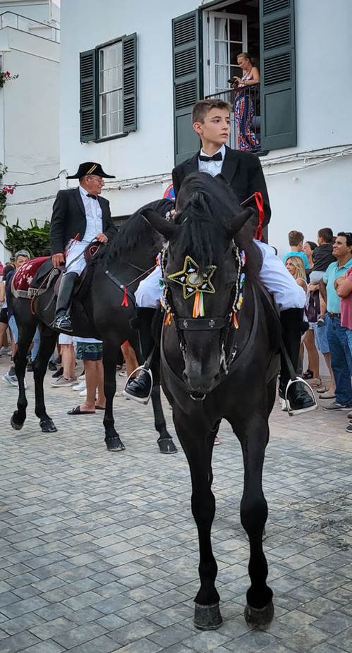 Un jeune cavalier fier pose avant la parade de la fête du cheval à Minorque, capturé au crépuscule avec un Galaxy Z Flip 3. La lumière douce met en valeur l’élégance et la tradition dans une ambiance authentique.