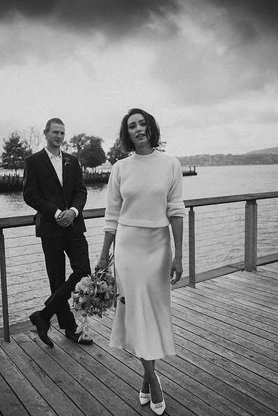 Bride in foreground with groom in background on a bridge, captured in black and white by a Connecticut wedding photographer.