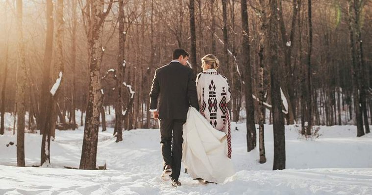 Couple walking away on a winter day in the Berkshires, Western Massachusetts, with the bride wearing a stylish sweater jacket, captured by a Connecticut wedding photographer.