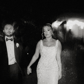 Black and white nighttime portrait of a couple standing close together, illuminated by soft ambient light with deep shadows creating a dramatic, intimate mood — photographed by a CT-based wedding