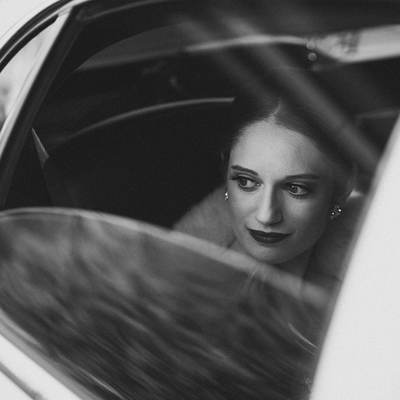 Bride looking out of a cracked car window, thoughtful and serene — captured by a CT-based wedding photographer.
