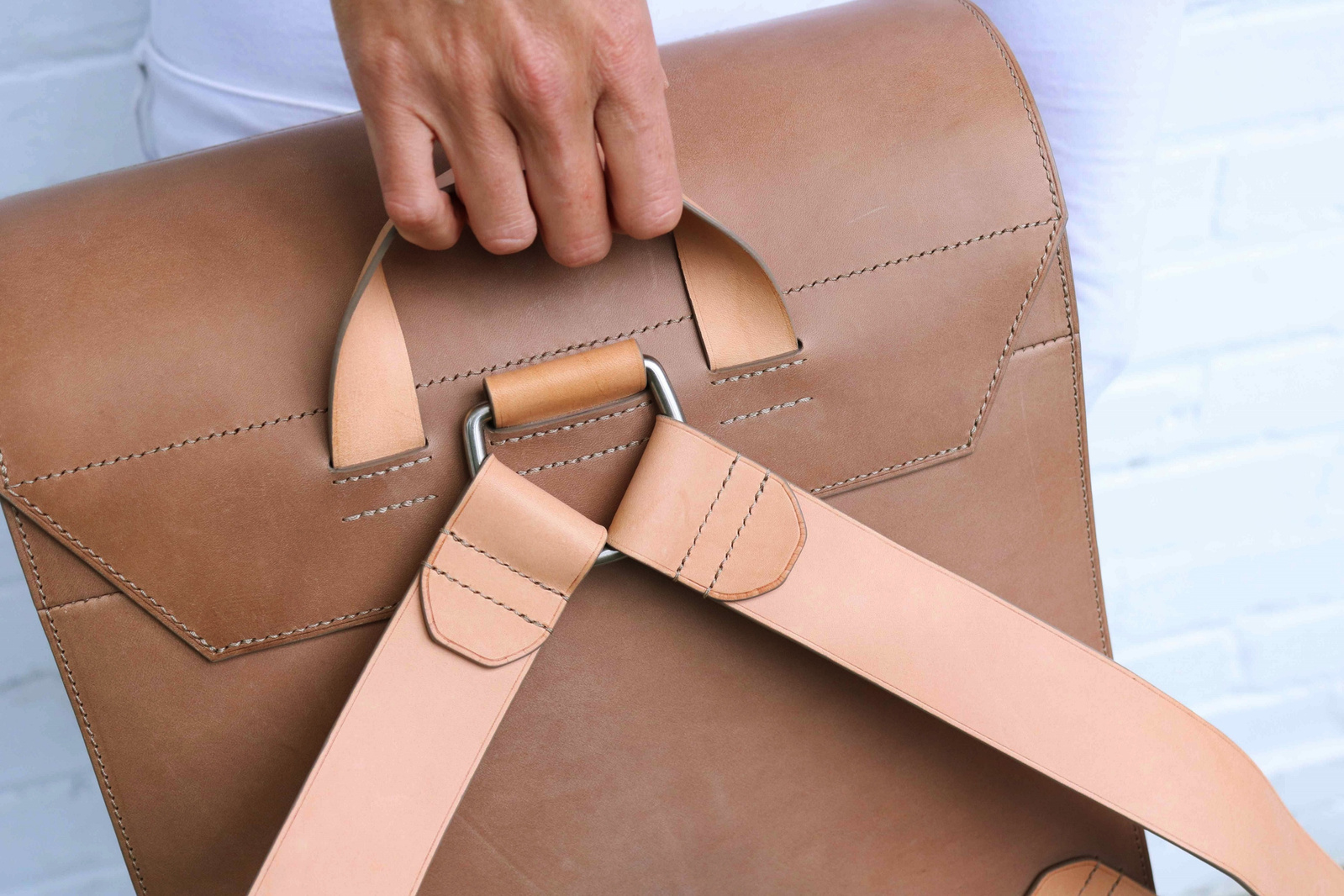 Les bretelles et la poignée du sac à dos sont en en cuir à tannage végétal naturel et cousu à la main, au point sellier, pour plus de solidité.