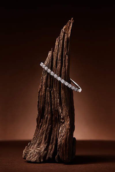 Silver bracelet sitting on top of driftwood in a studio jewellery shoot with deep brown beige colours. Photographed by commercial photographer Karan Gill based in melbourne.