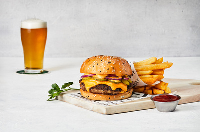 Cheeseburger and fries with a beer displayed on a white bright background. Photographed by a professional food photographer for a business menu photography.