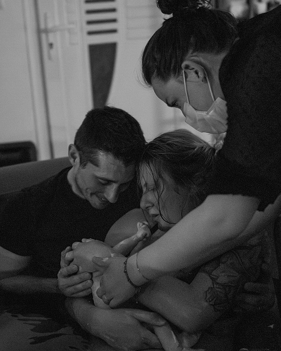 Naissance du bébé, dans les bras de ses parents, sous le regard de la sage-femme