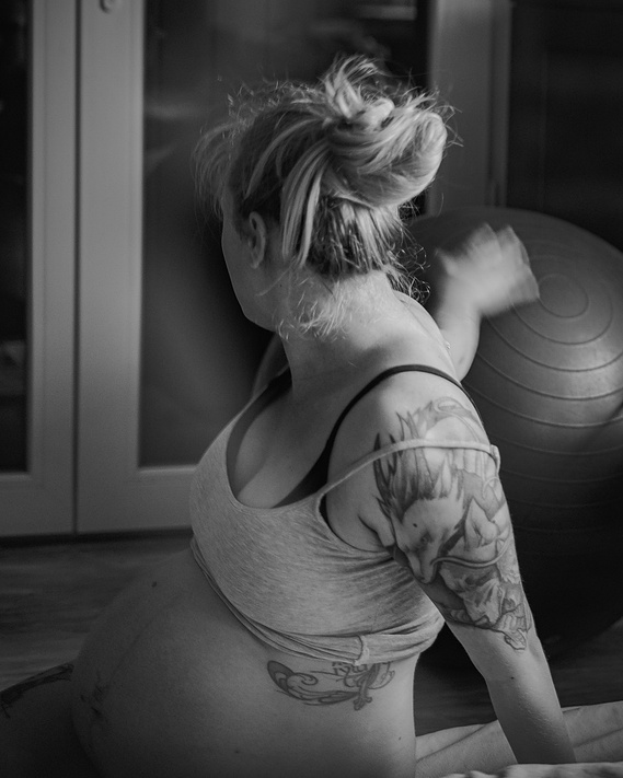 Une femme assise au sol attrape un ballon de yoga