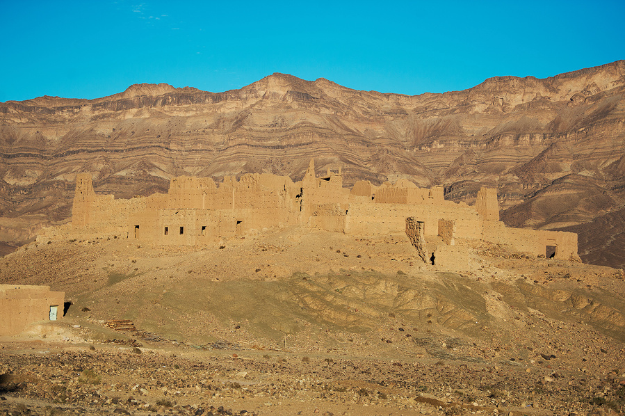 An old monument in front of a mountain in the same color tone, in Draa Valley of Morocco. 
