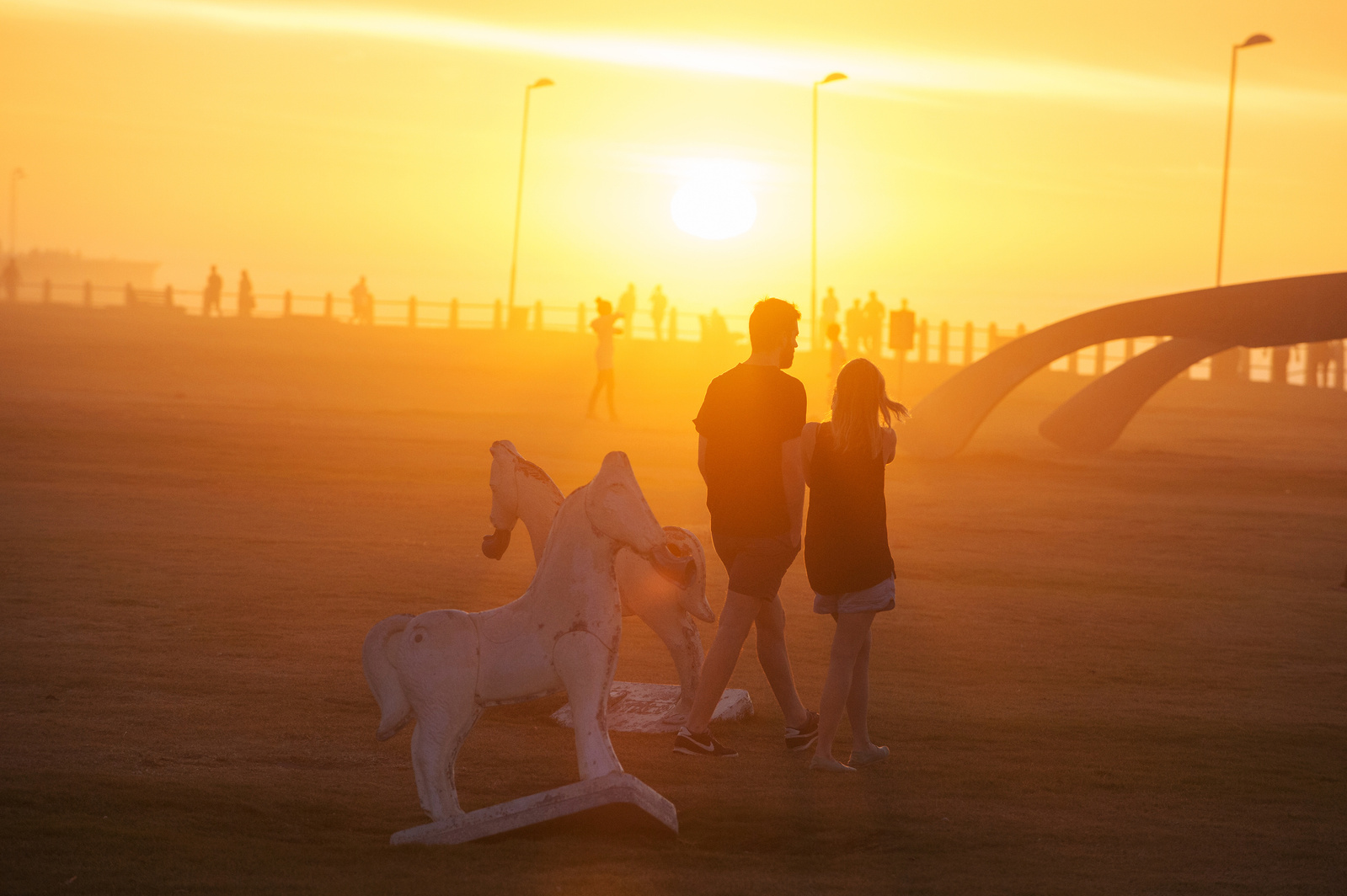 The sun sets as a couple strolls down the boulevard in Cape Town, South Africa.