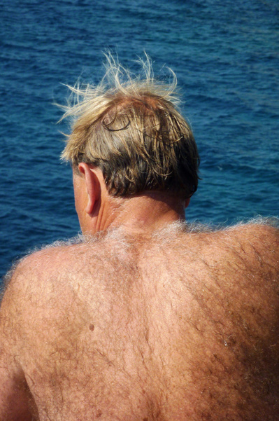 Señor peludo con el torso desnudo y el pelo al viento con el mar de fondo David Salcedo