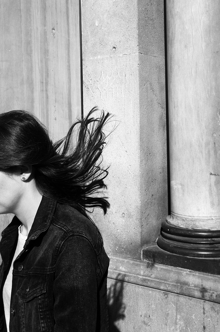Mujer caminando saliendo de la imagen por la izquierda y con el pelo volando por el viento David Salcedo