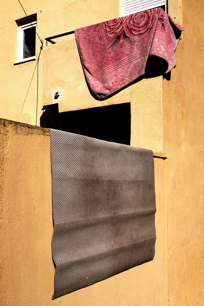 Dos alfombras secándose al sol en una pared naranja David Salcedo
