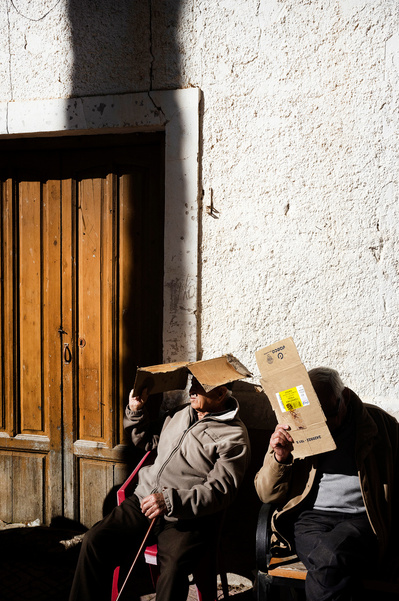 Dos señores mayores protegiéndose del sol con dos cartones David Salcedo