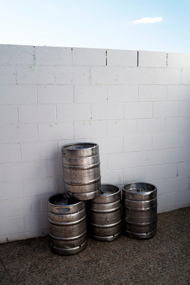 Barriles de cerveza usado con tapia blanca de fondo David Salcedo
