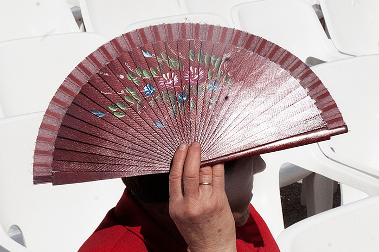 Señora protegiéndose del sol con abanico en las fiestas de la cruz  David Salcedo