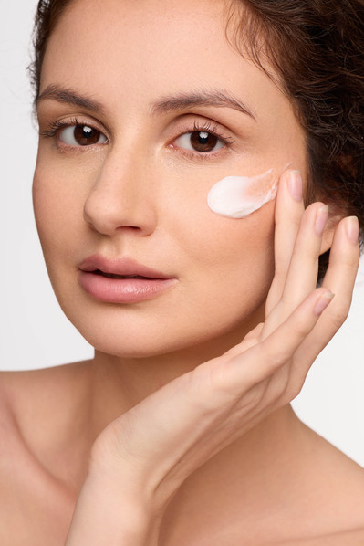 NYC skincare photographer capturing model applying moisturizer in studio.