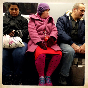 A woman wearing all pink standing out in a subway car in New York City