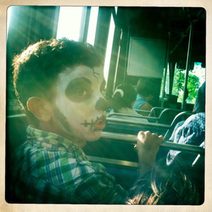 A boy in skull facepaint on the bus