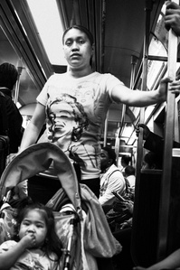 A mother wearing a Marilyn Monroe t-shirt, with her kid in a stroller in the New York City subway