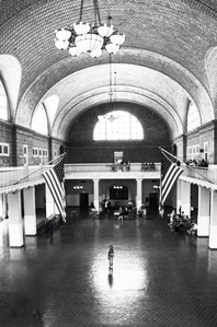 Ellis Island tourist, standing in the light between two American flags