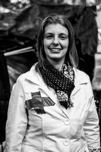 A black and white photo of a medic at Zuccotti Park, smiling for the camera during Occupy Wall Street