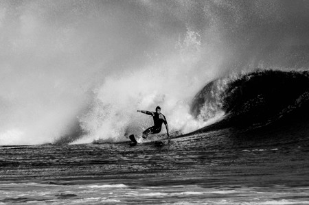 A black and white photo of a surfer shooting out of the tube in Rockaway Queens, NYC