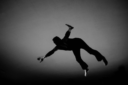 A black and white photo of a wrestler flying towards the outside during a wrestling match in Brooklyn NY.