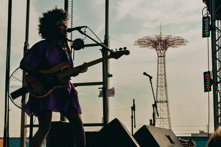 Kamara Thomas of Earl Grayhound singing into a microphone as the Coney Island Parachute Jump is in the background