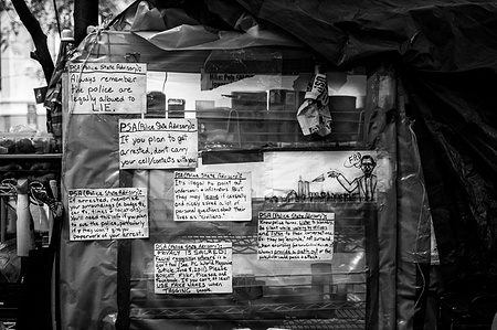 PSAs on cardboard signs on how to handle interactions with the police, at Zuccotti Park during Occupy Wall Street