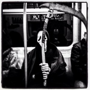 A person dressed as death sitting in a subway car in the New York City subway