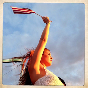 A pretty red headed girl holding up the American flag during an independence day celebration in Brooklyn NY. 