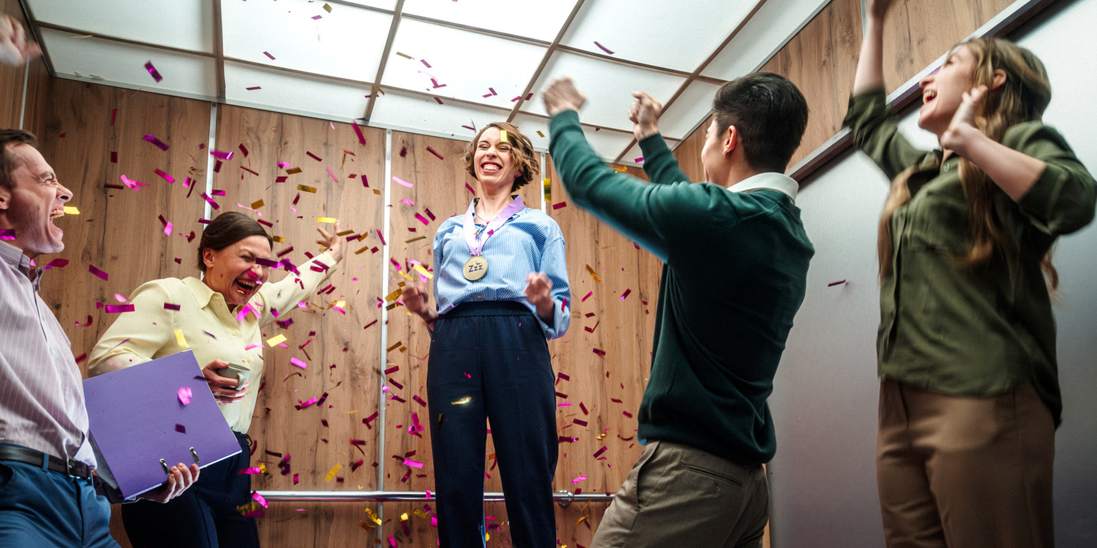 a woman celebrating end of the day in elevator with her work colleagues 