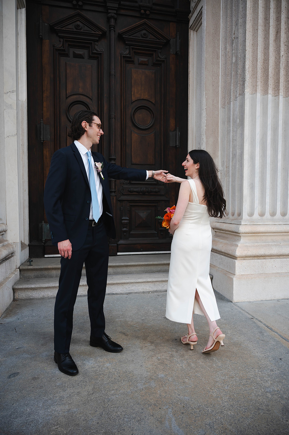 Bride and groom standing in front of the dark brown doors of the Tweed Courthouse in NYC
