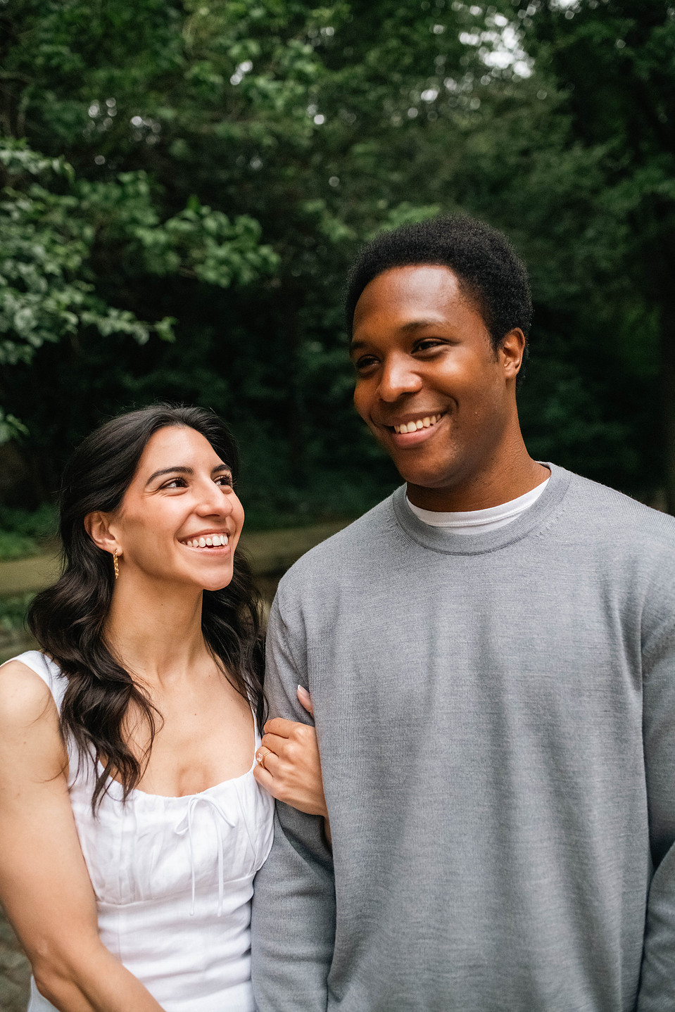 Engaged couple walking hand-in-hand under trees in Prospect Park during a Brooklyn engagement session