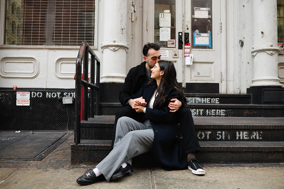 Engaged couple sitting on cobblestone streets of SoHo, New York City