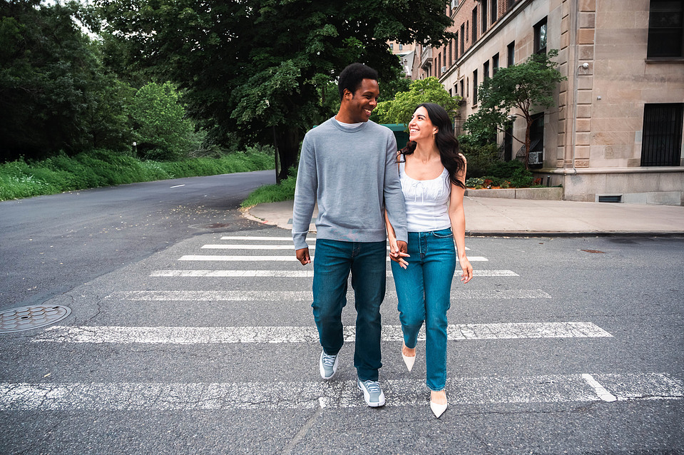 Engaged couple walking hand-in-hand under trees in Prospect Park during a Brooklyn engagement session