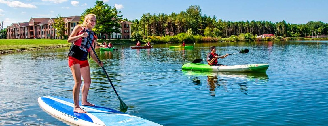 A female student at Lake Michigan College takes a paddle board out on one of the many water areas on campus. 