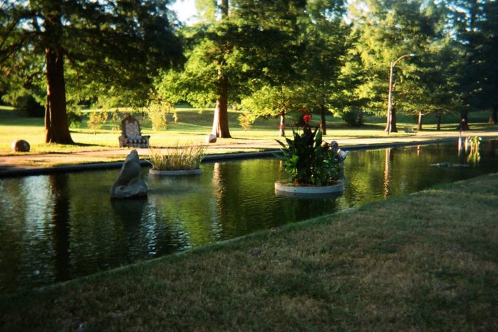 A canal of water runs through the center of a grassy park.